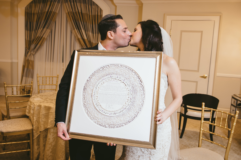 A photo of a couple holding their signed Ketubah, symbolizing their commitment to each other